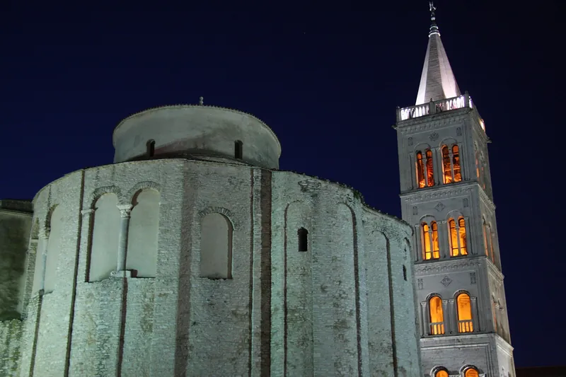 The round Church of St. Donatus and the lit cathedral bell tower at night, Zadar
